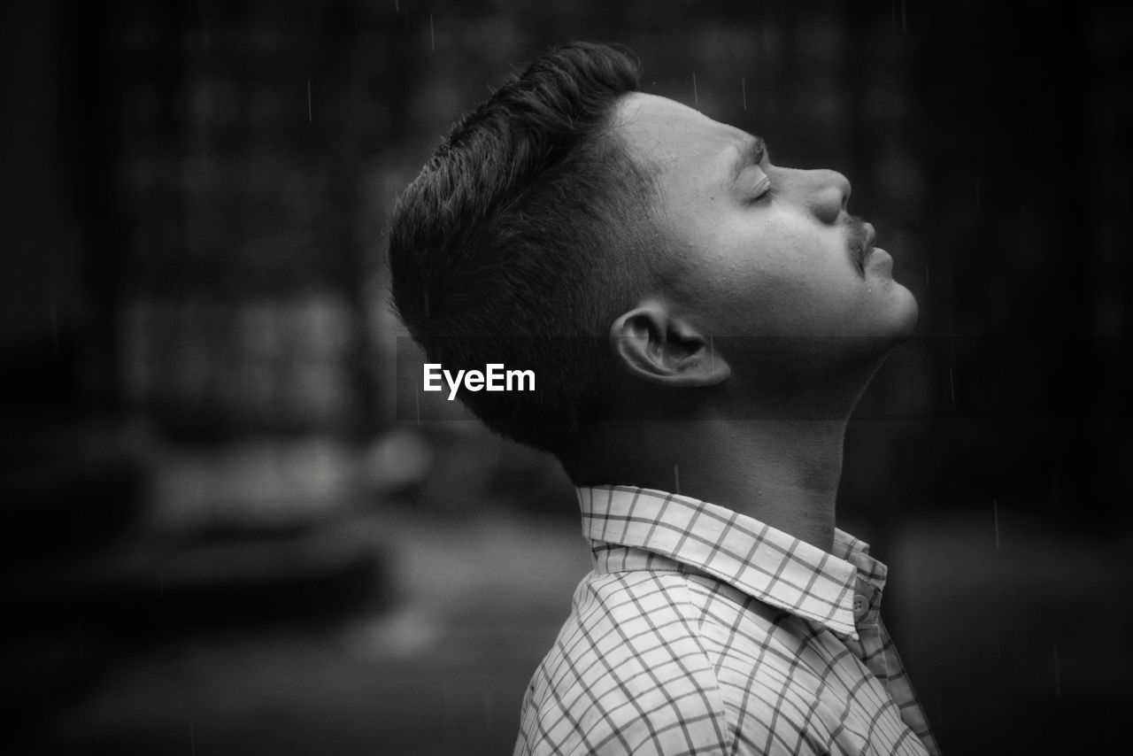 Side view of young man with eyes closed standing outdoors