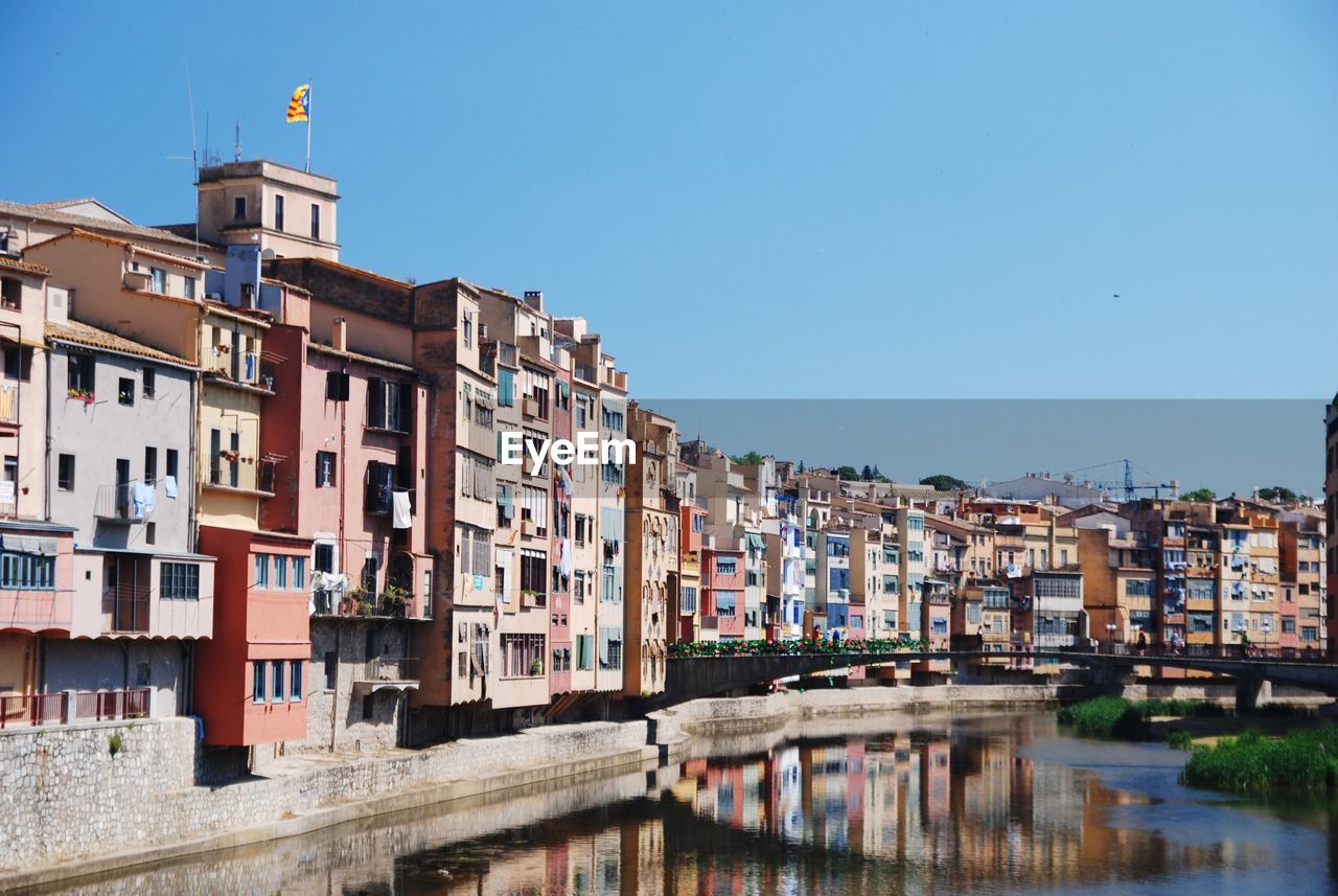 Residential buildings by canal against clear sky