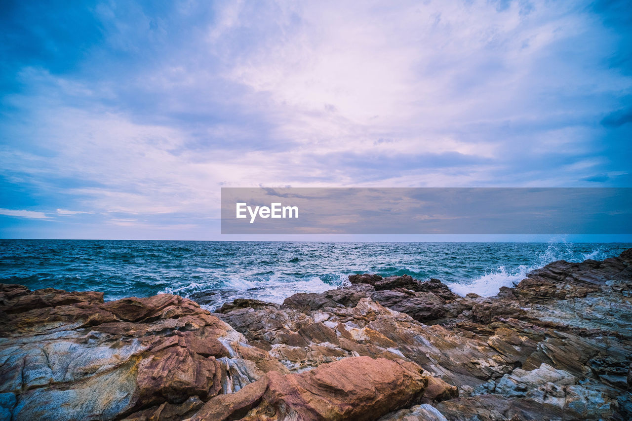 ROCKS BY SEA AGAINST SKY