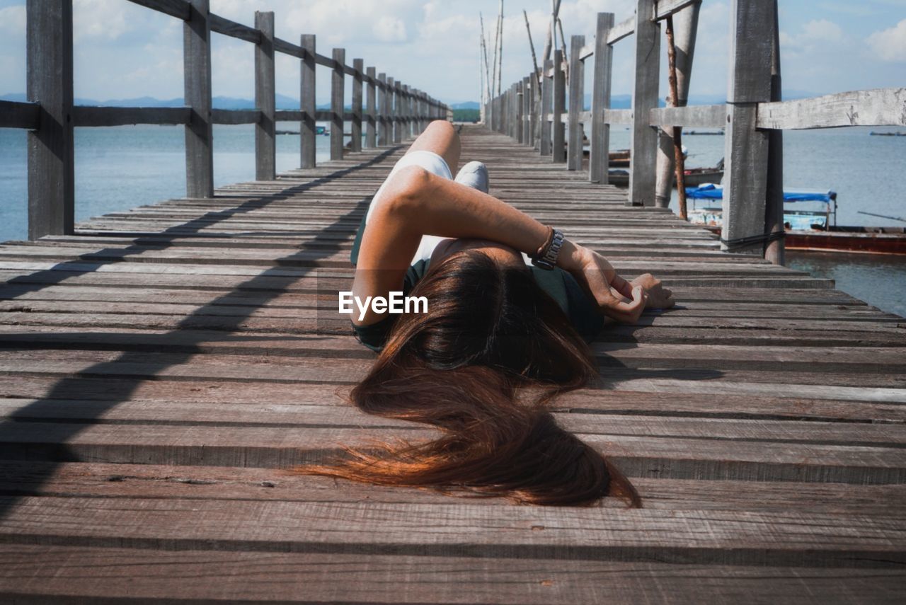 Woman relaxing on pier over sea