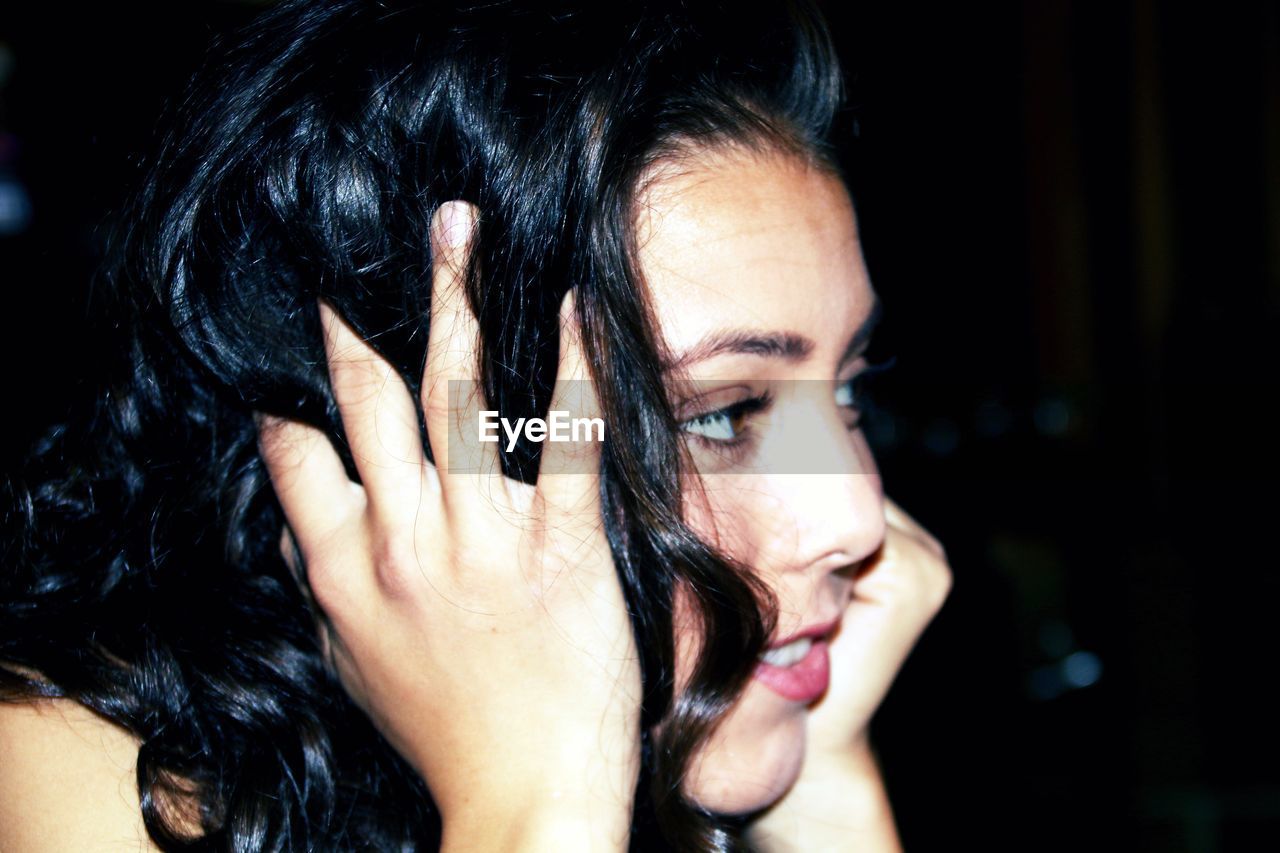 CLOSE-UP PORTRAIT OF A WOMAN WITH HAND ON HAIR