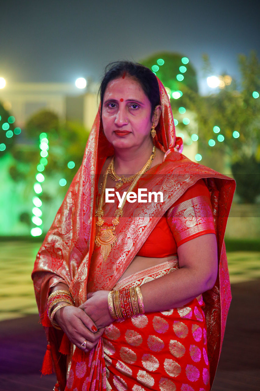 Portrait of young woman standing wearing red saree 