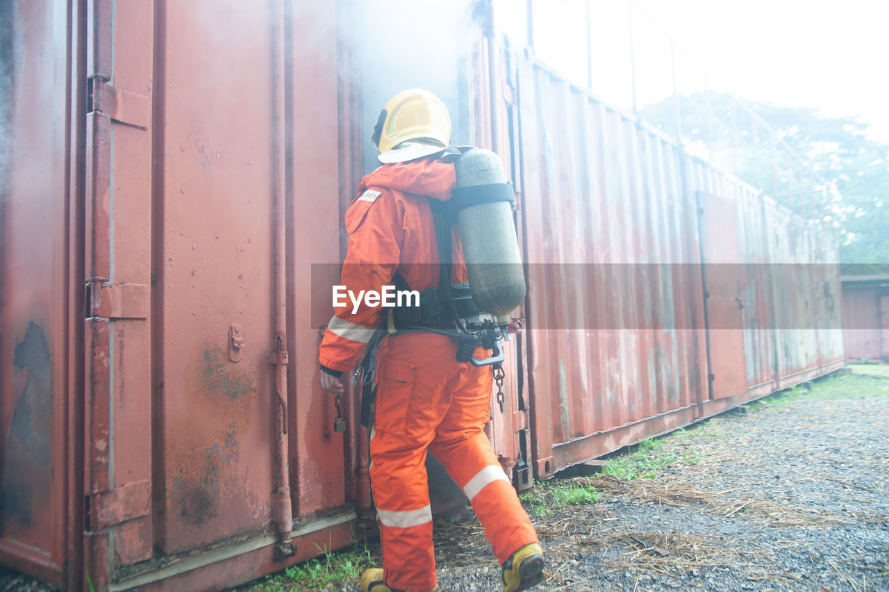 REAR VIEW OF MAN WORKING ON METAL STRUCTURE