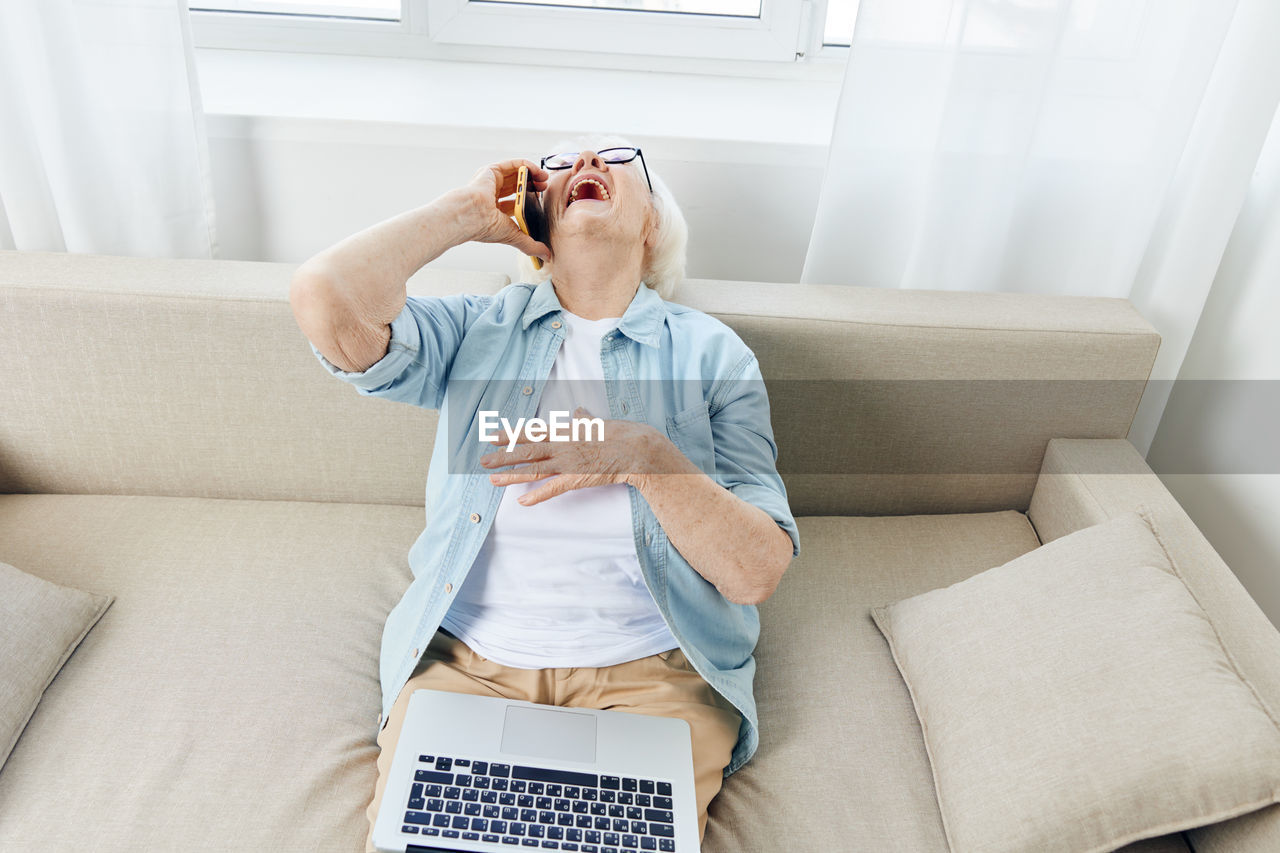 low section of woman using laptop while sitting on sofa at home