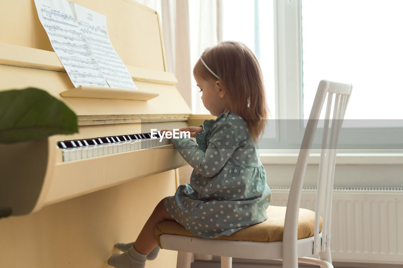 Little girl playing on yellow piano
