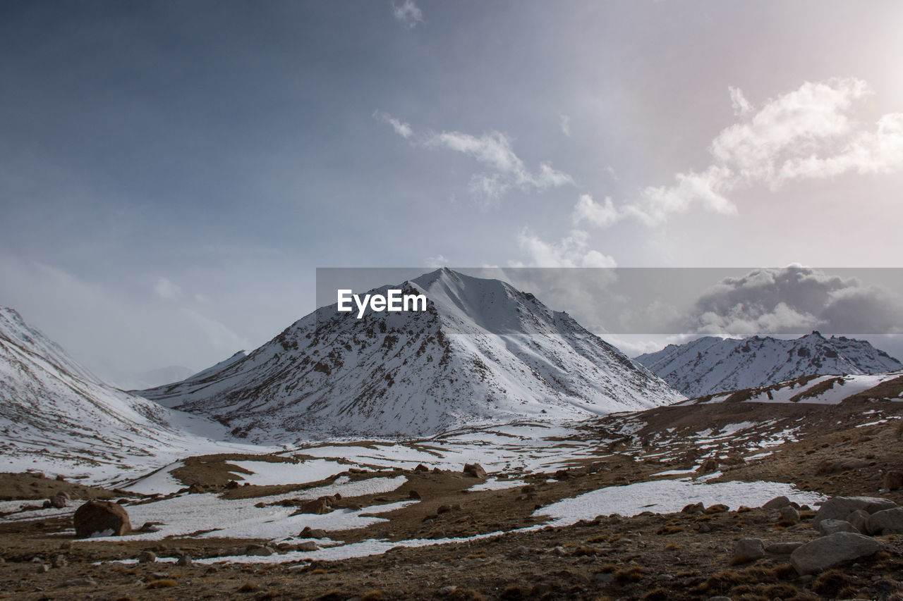 Scenic view of snowcapped mountains against cloudy sky