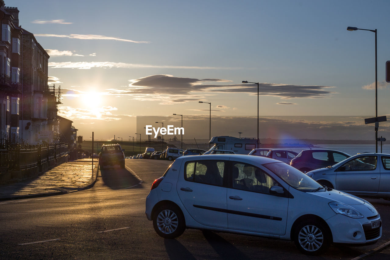 CARS ON STREET AGAINST SKY AT SUNSET