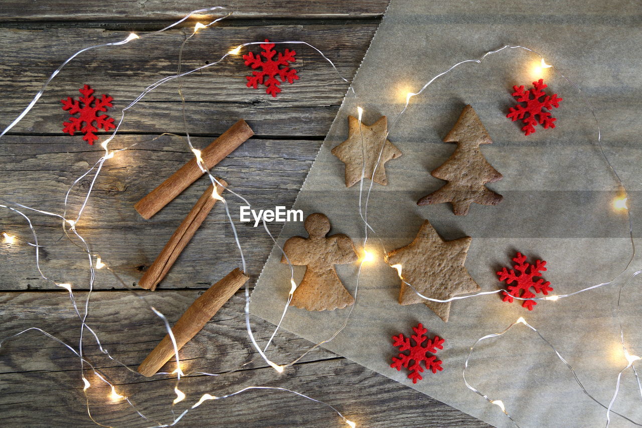 Cookies with cinnamon and hazelnuts by artificial snowflakes on illuminated wooden table