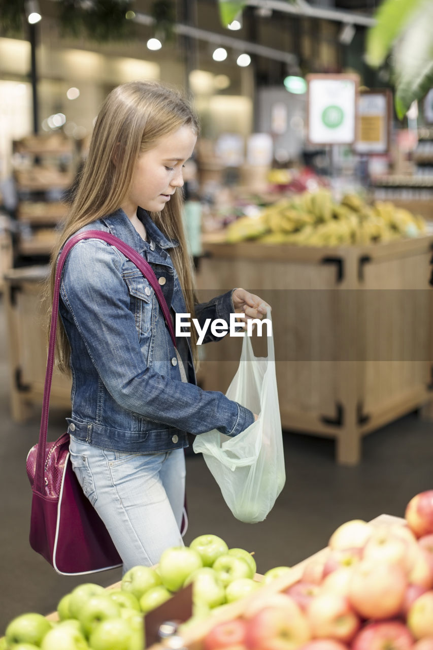 Girl buying apples in supermarket