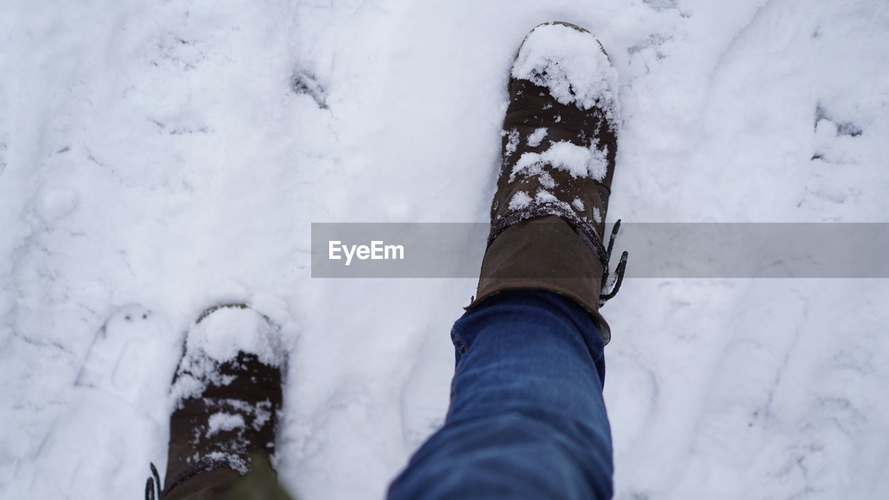 Low section of person wearing snow covered shoes