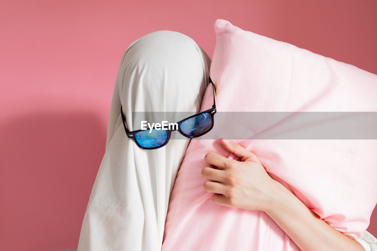 Cute sheet ghost costume with sunglasses on a pink background. halloween party carnival concept.