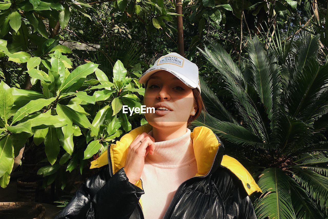 Portrait of young woman standing against plants