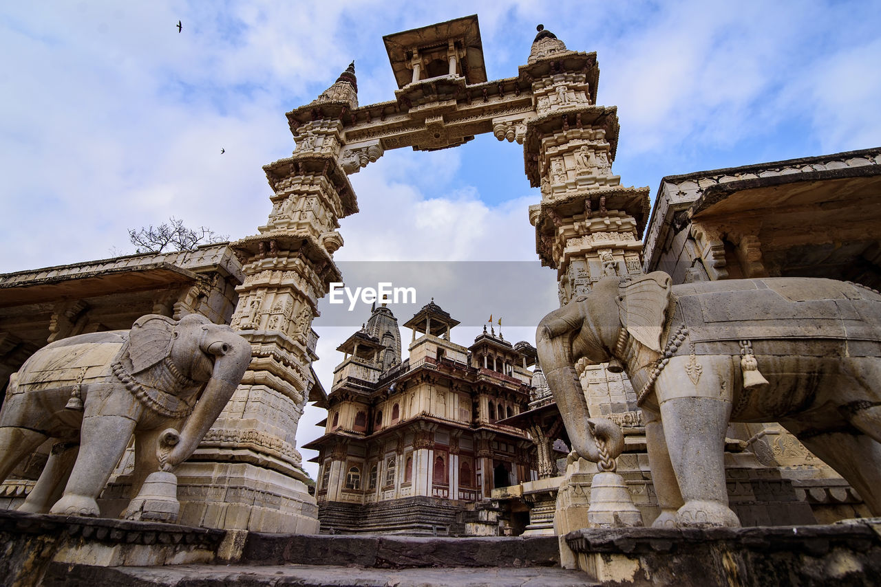 Low angle view of statues at temple entrance against sky