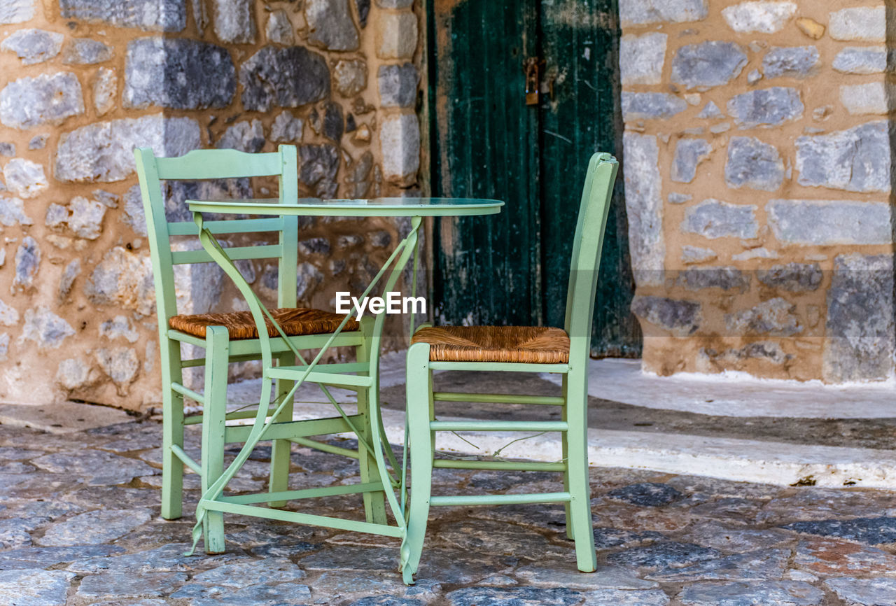 Empty chair against wall of old building