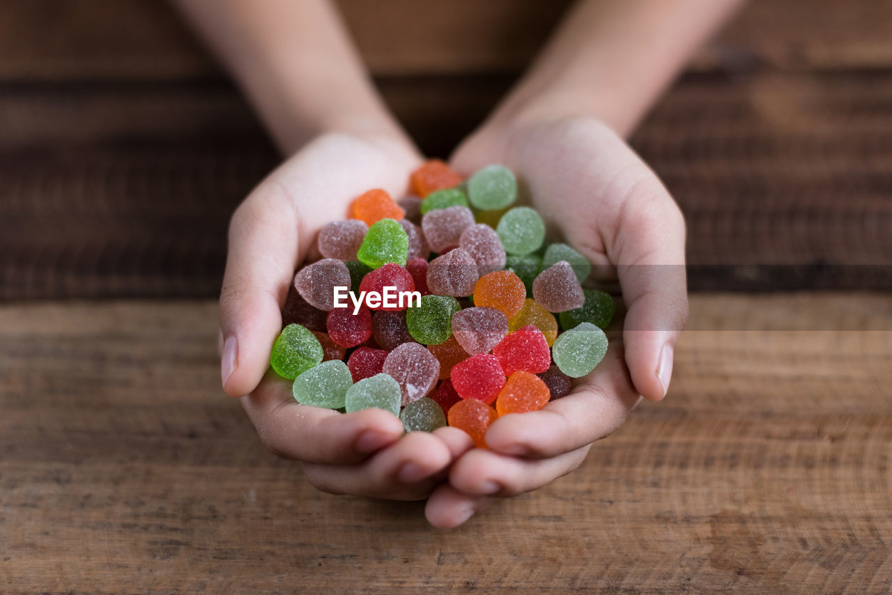 Cropped hands of woman holding colorful candies on table