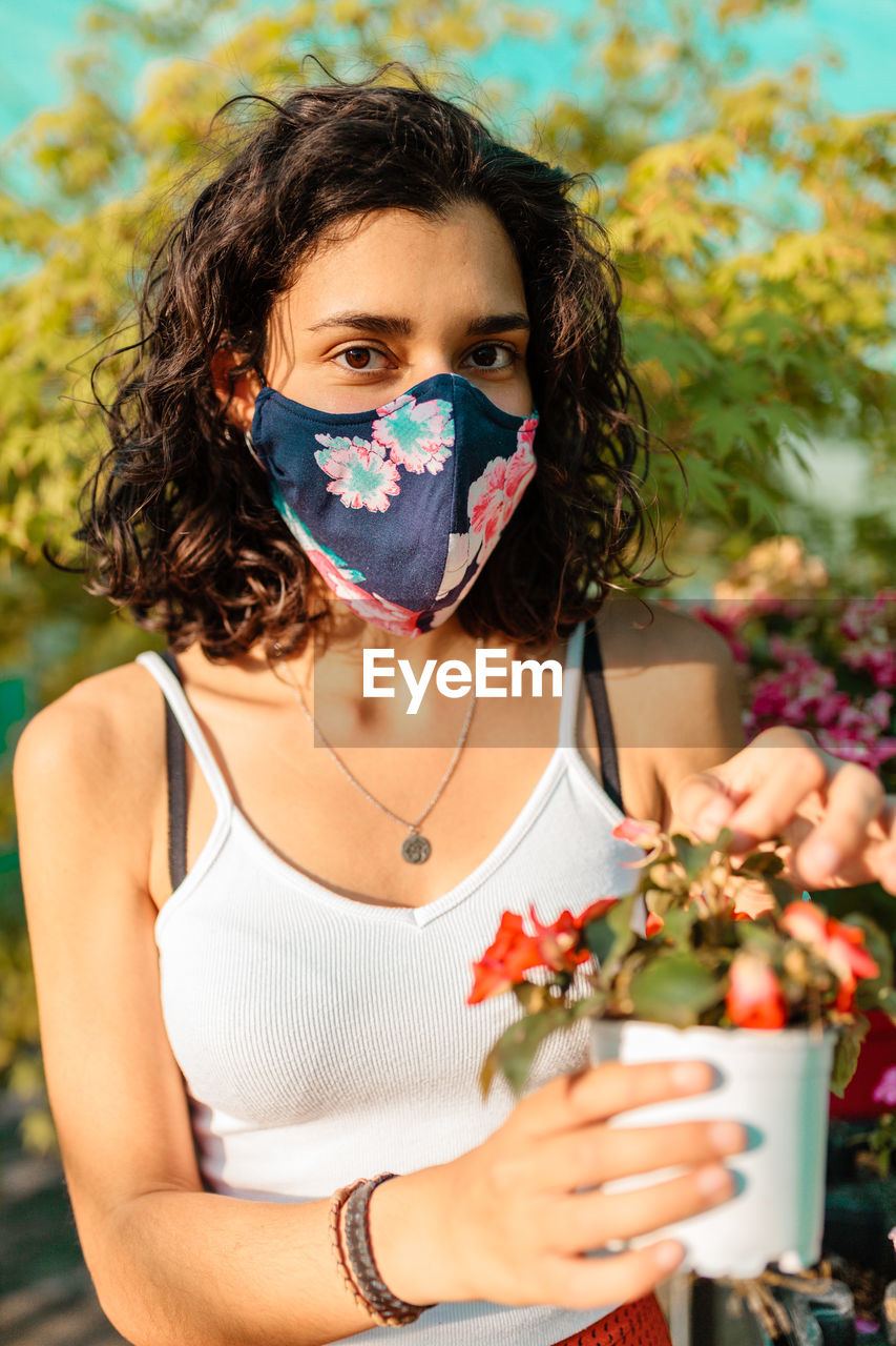 Portrait of teenage girl holding red flowering plant