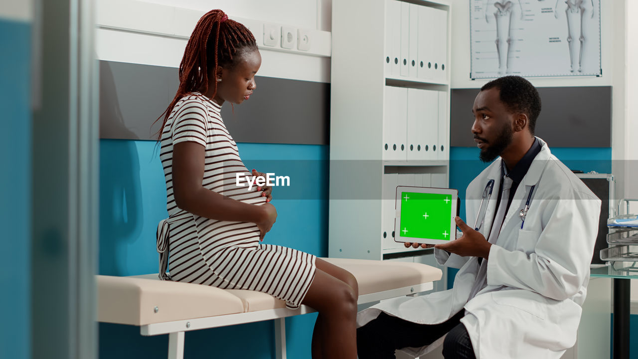 Doctor holding digital tablet while discussing with patient