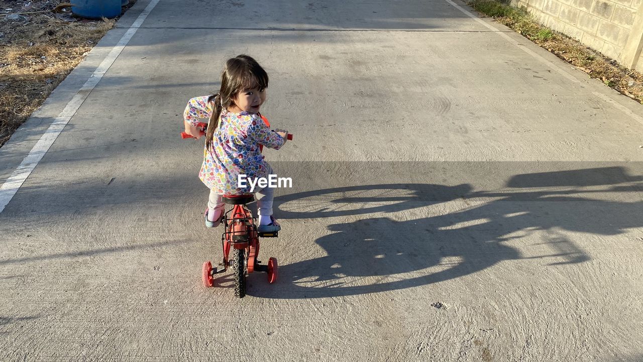 Rear view of girl bicycling on road