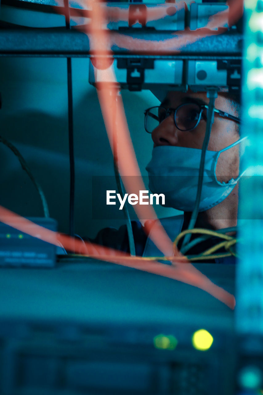 An computer science enegeneer work on his network picture took behind cables and wires 