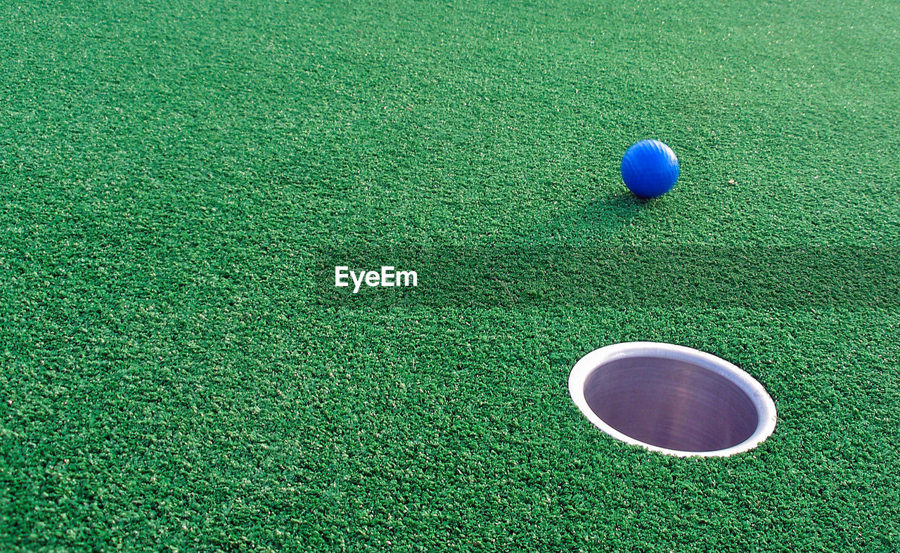 Adventure golf, ball rolling towards hole.