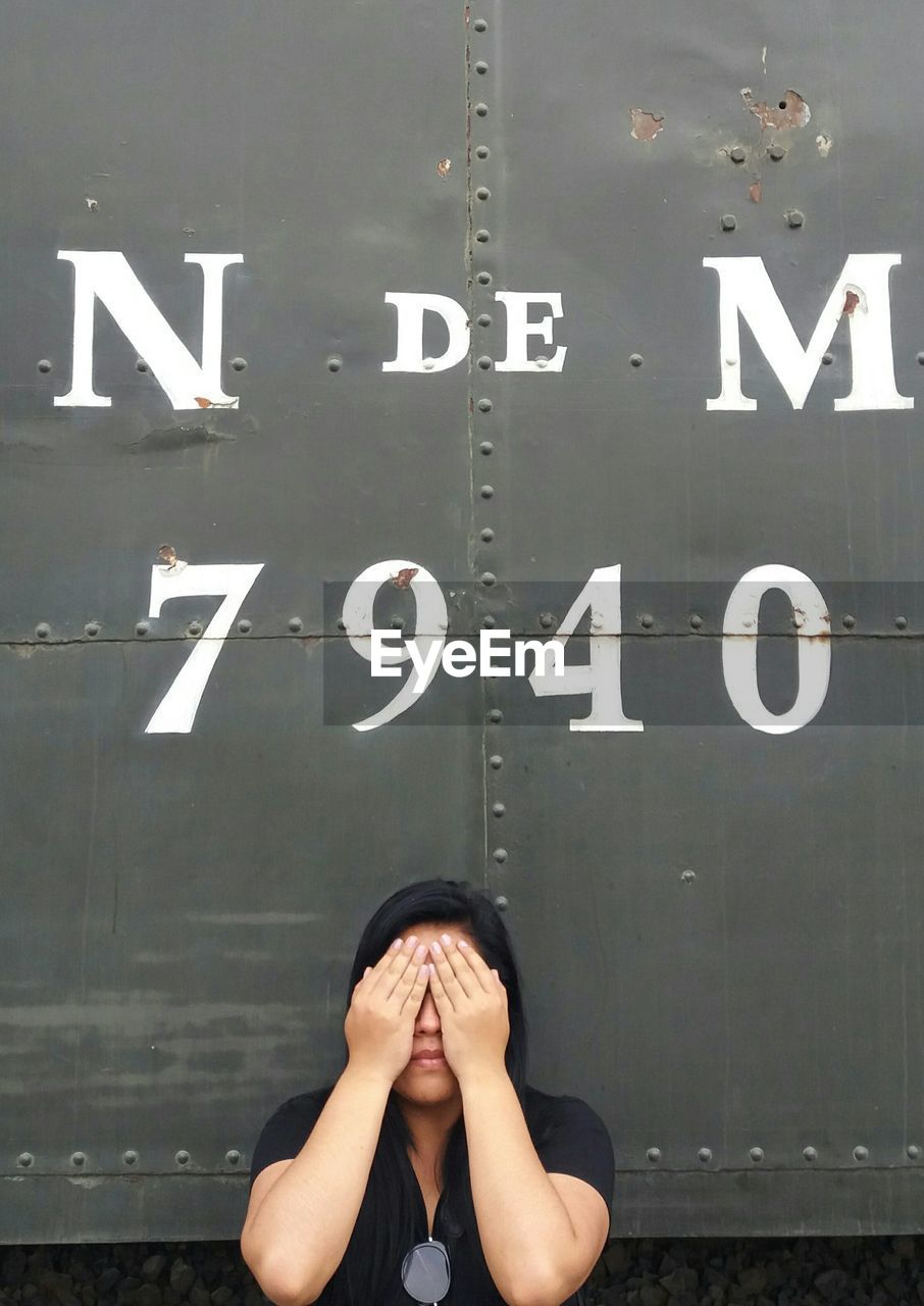 LOW ANGLE VIEW OF WOMAN WITH TEXT ON WALL