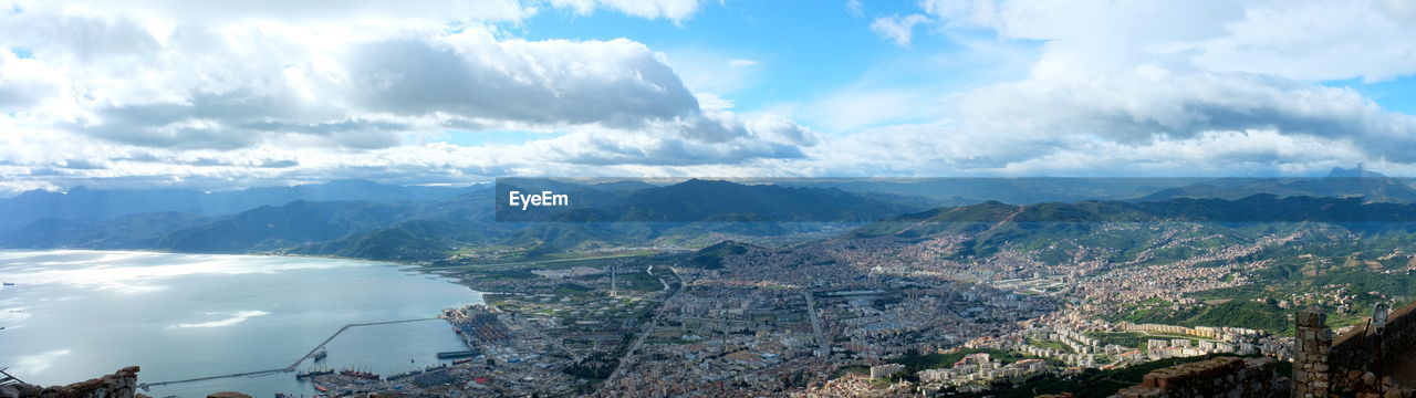 Panoramic shot of landscape and sea against cloudy sky