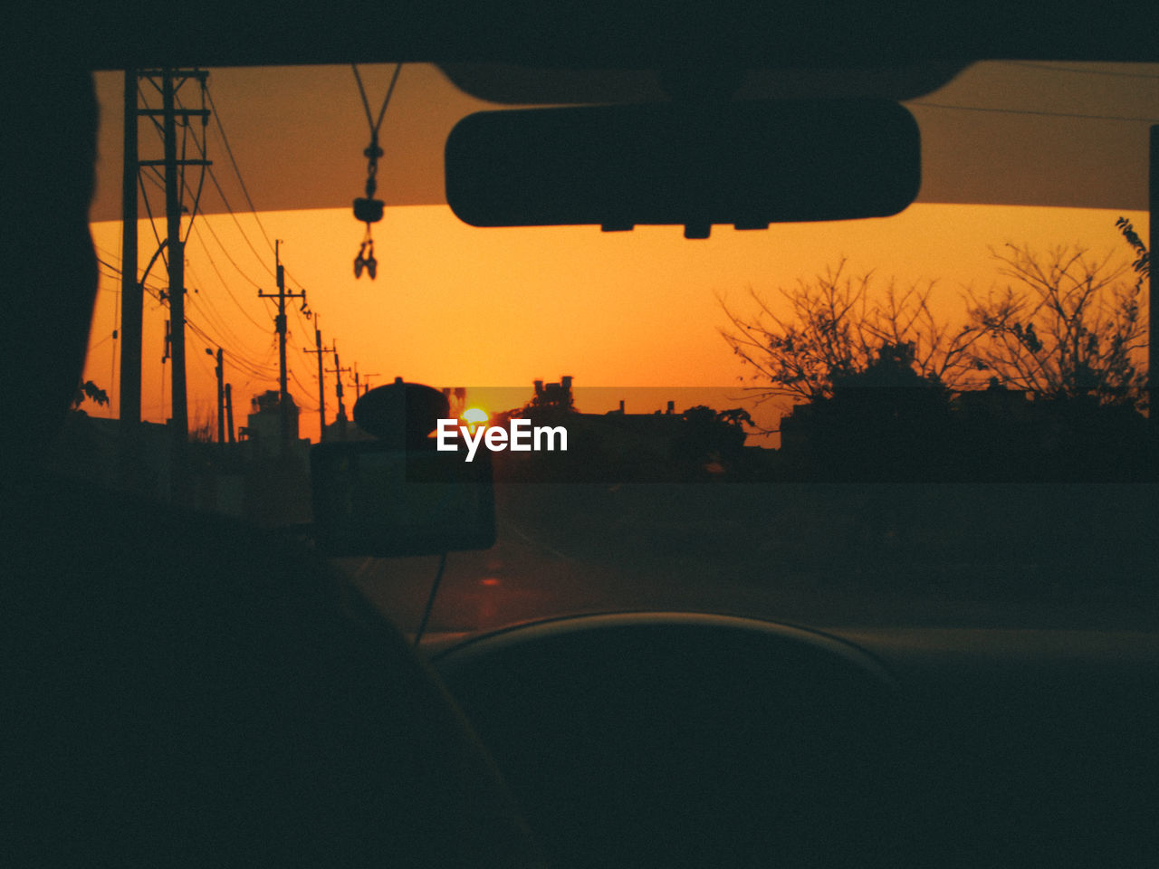 Rear view of silhouette man in car against orange sky