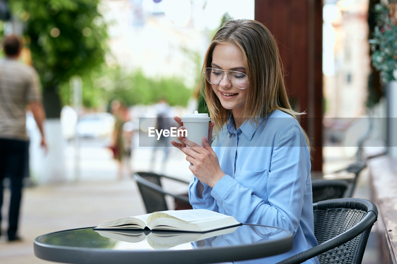 portrait of young businesswoman using mobile phone while sitting in cafe