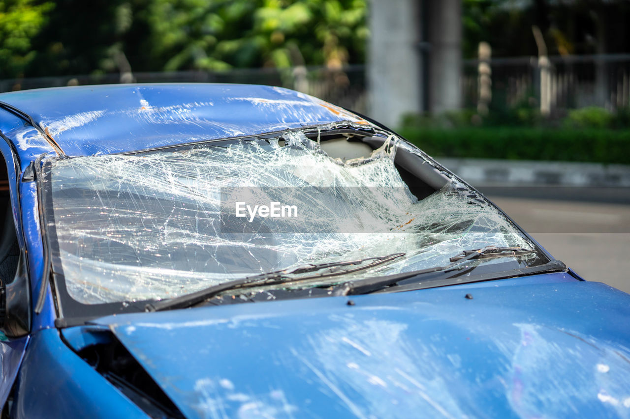 CLOSE-UP OF BROKEN GLASS AGAINST CAR