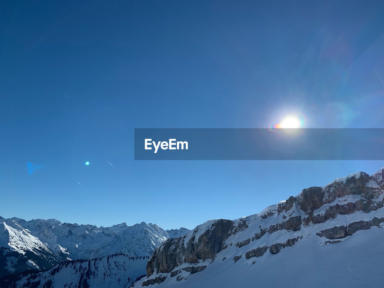 Scenic view of snowcapped mountains against blue sky