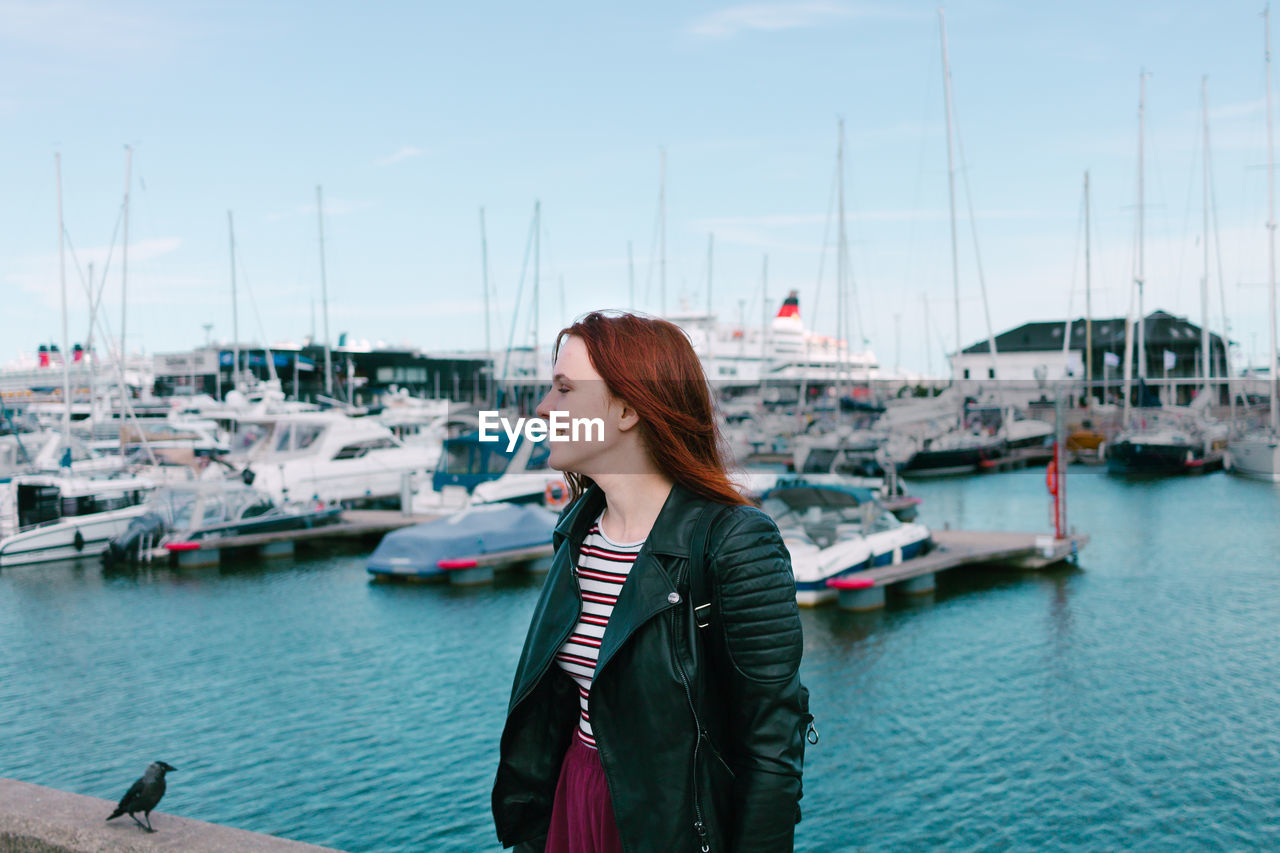 Woman looking away while standing at harbor