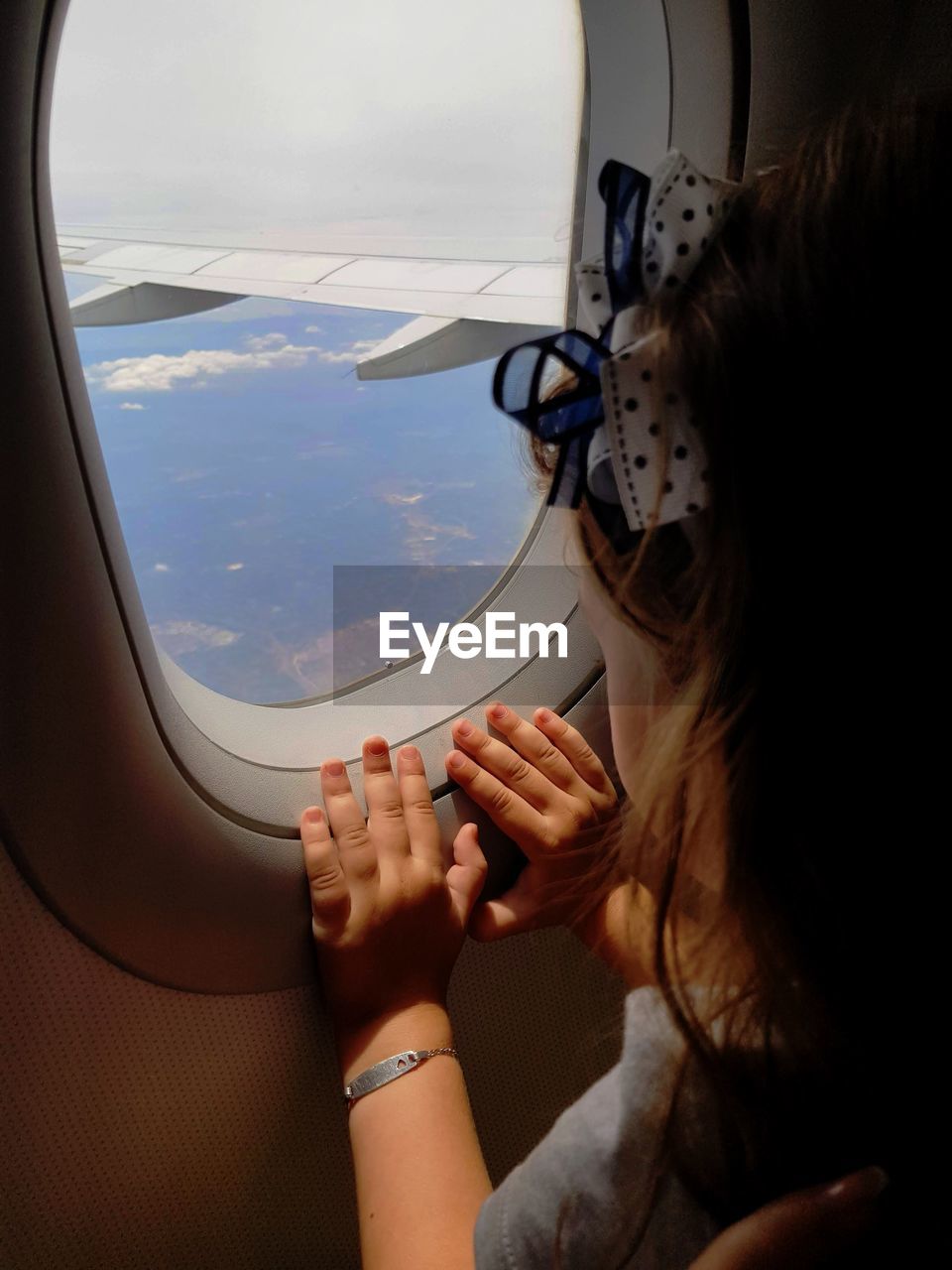 Little girl looking outside airplane window