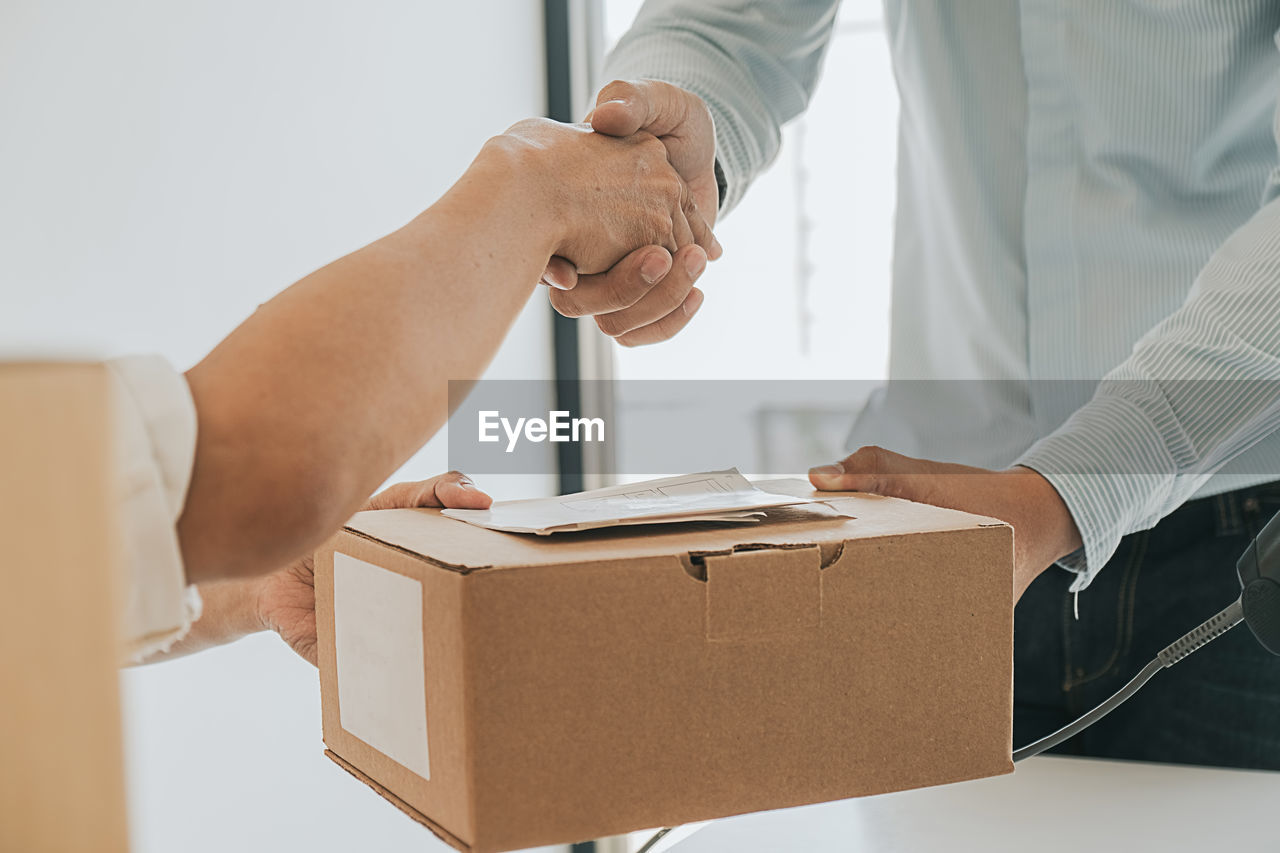 Midsection of people shaking hands at office