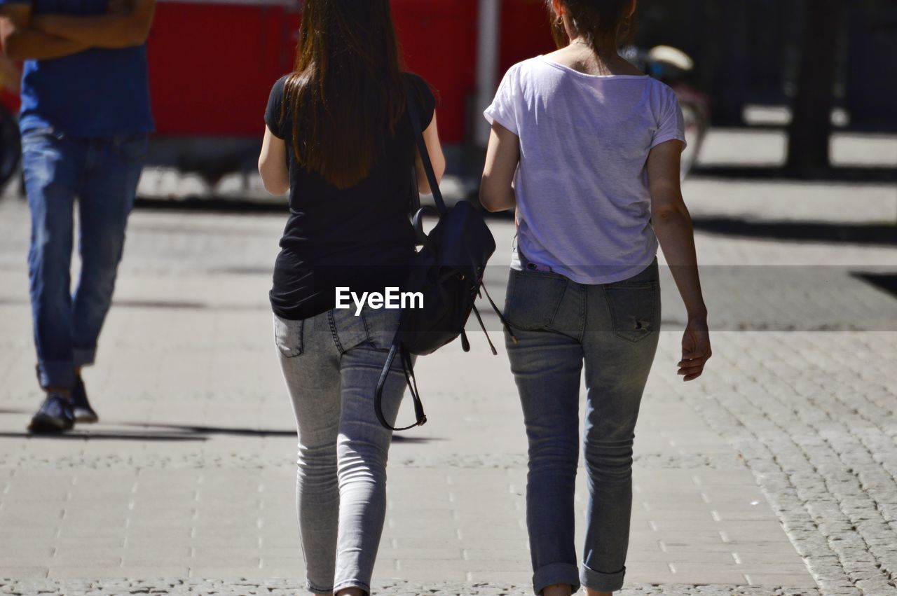 Rear view of women walking on sidewalk