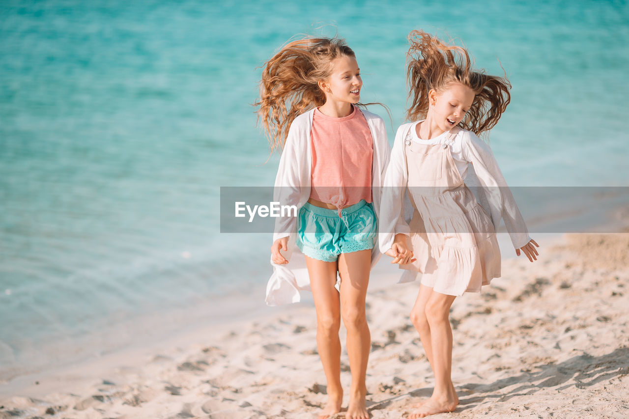 Sisters holding hands while standing on beach