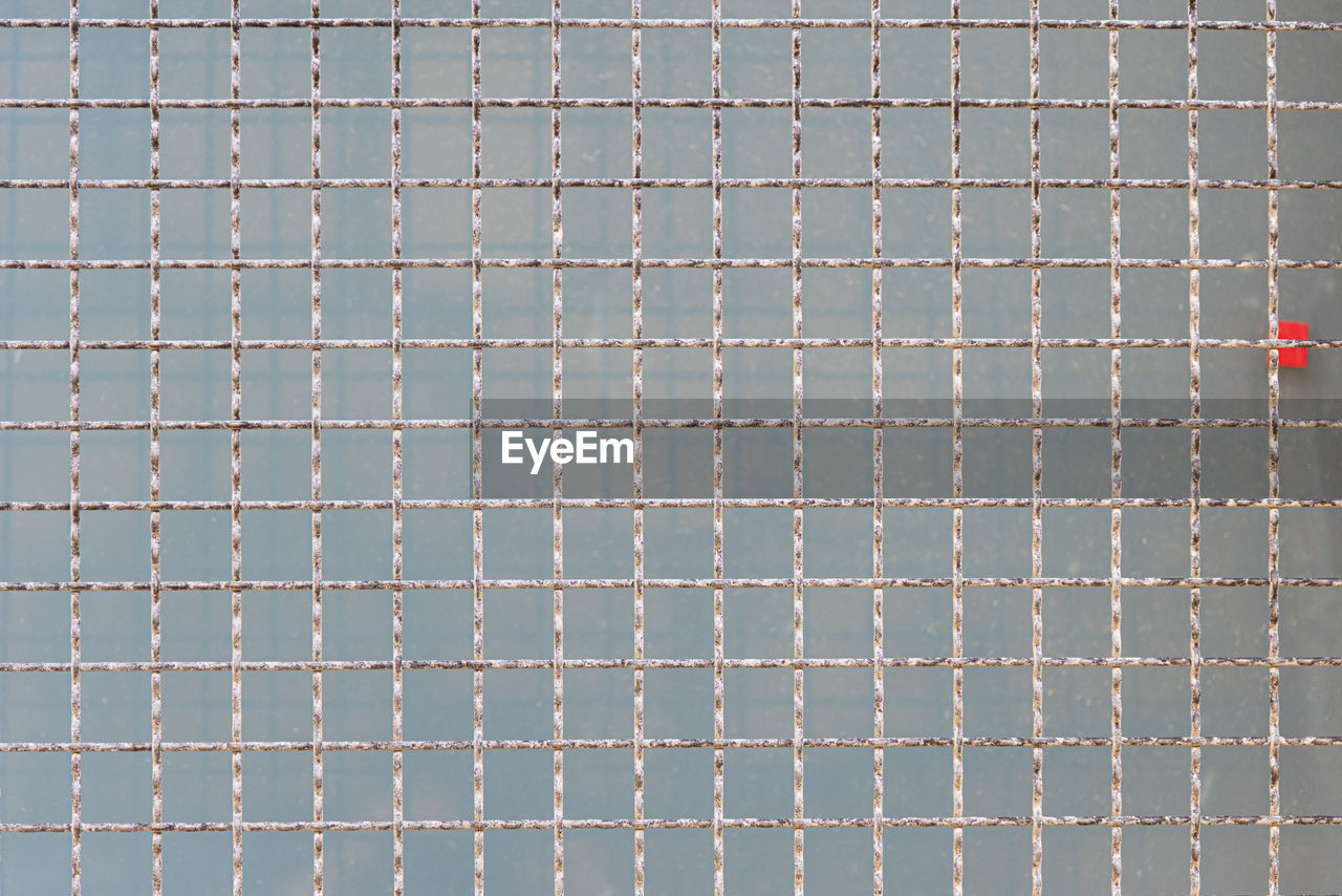 Metal grid on a concrete block background