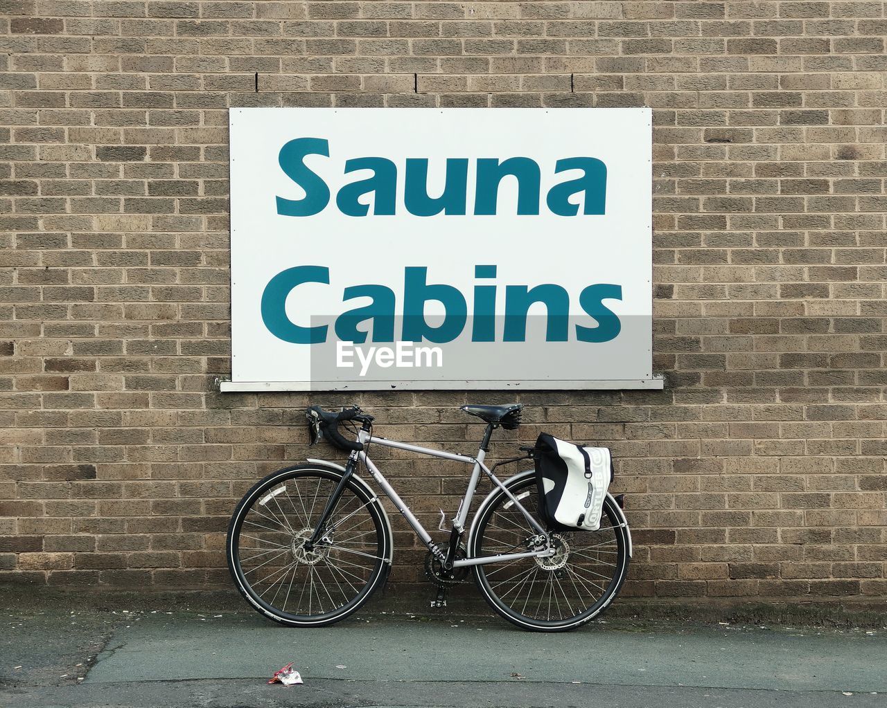 Bicycle parked below sign on wall
