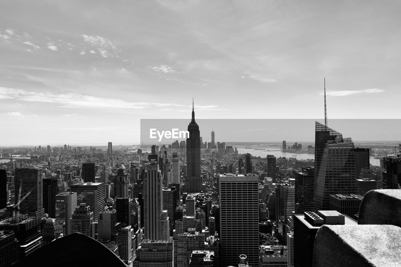 Aerial view of buildings in city against cloudy sky