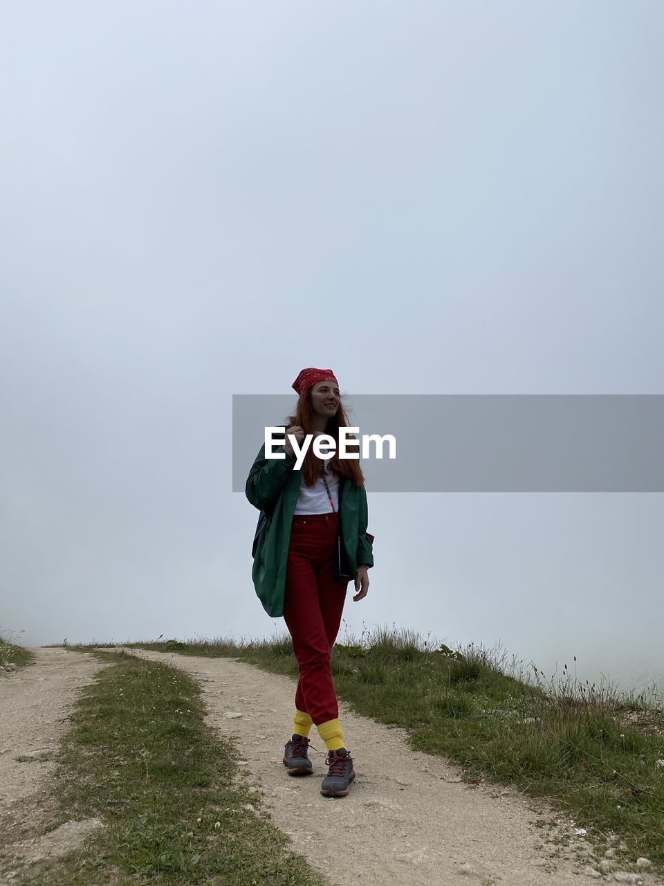 Full length of young woman standing against sky