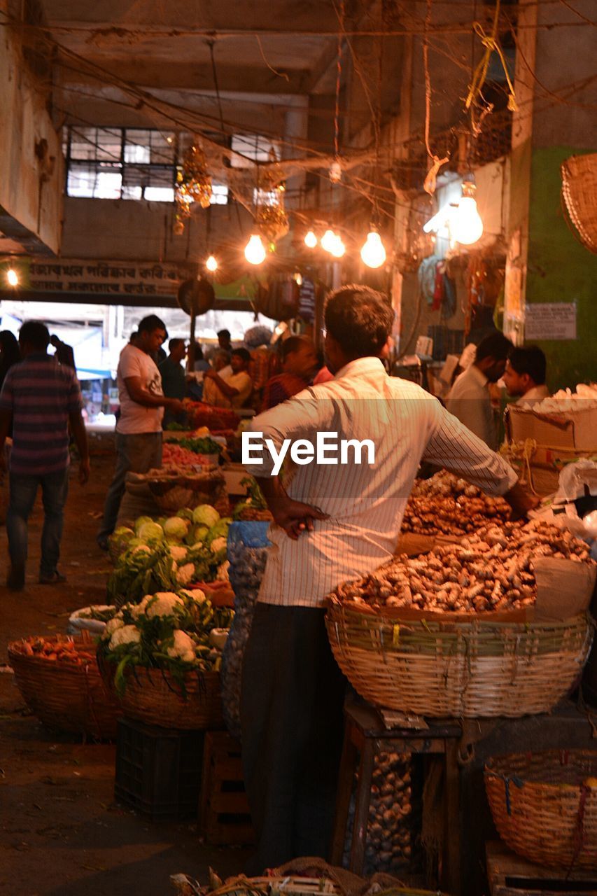 REAR VIEW OF PEOPLE WORKING AT MARKET