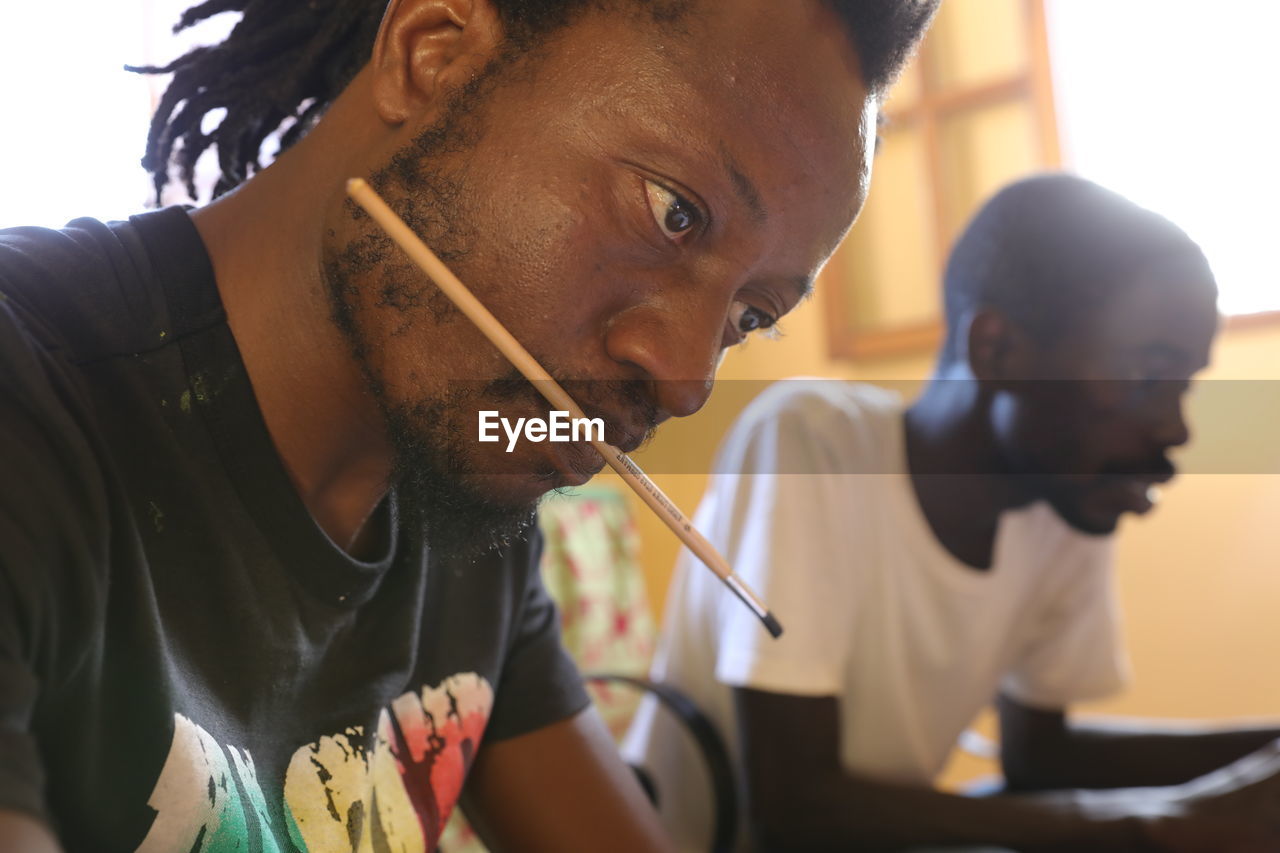 PORTRAIT OF YOUNG MAN LOOKING THROUGH CAMERA