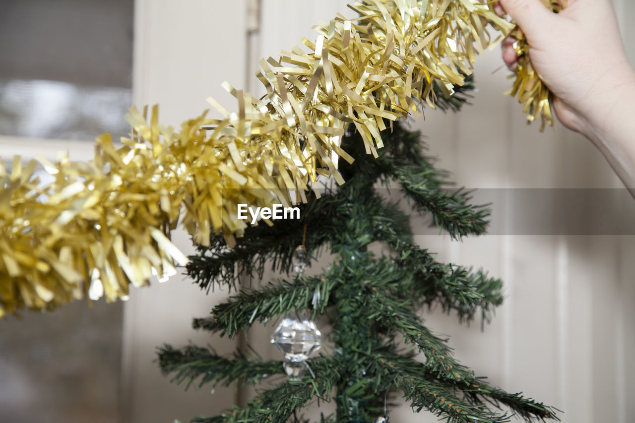 Close-up of hand decorating christmas tree