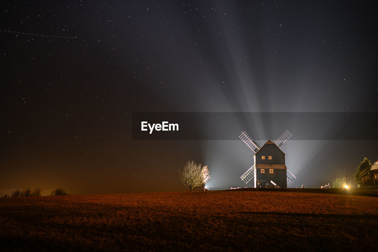 Scenic view of illuminated field against sky at night