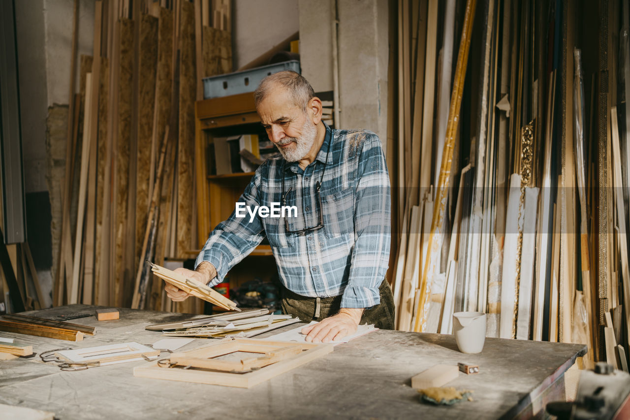 Senior carpenter examining picture frame at workshop