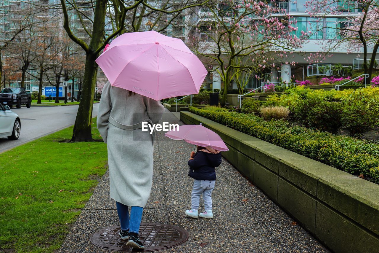 WOMAN WALKING ON WET FOOTPATH DURING RAINY SEASON