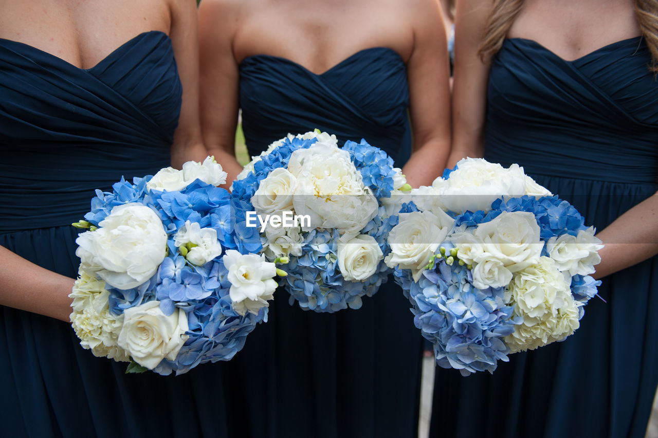 Midsection of bridesmaid holding bouquets