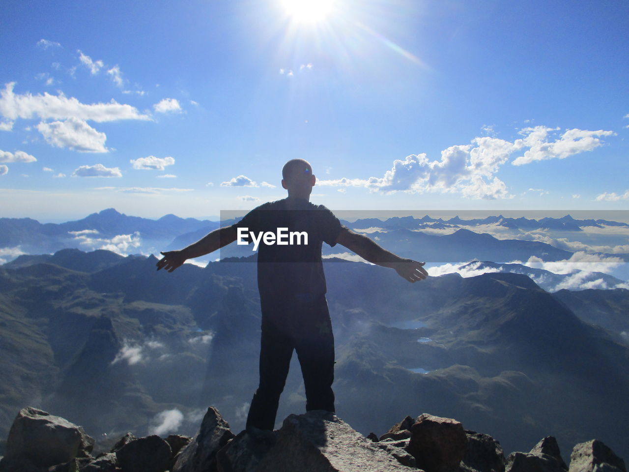 MAN STANDING ON ROCK AGAINST SKY