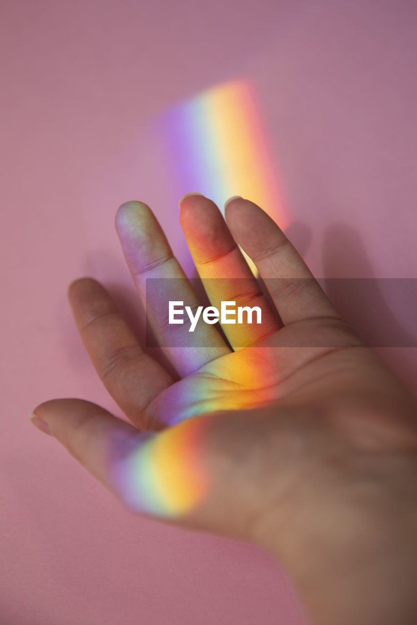 Close-up of human hand against pink background