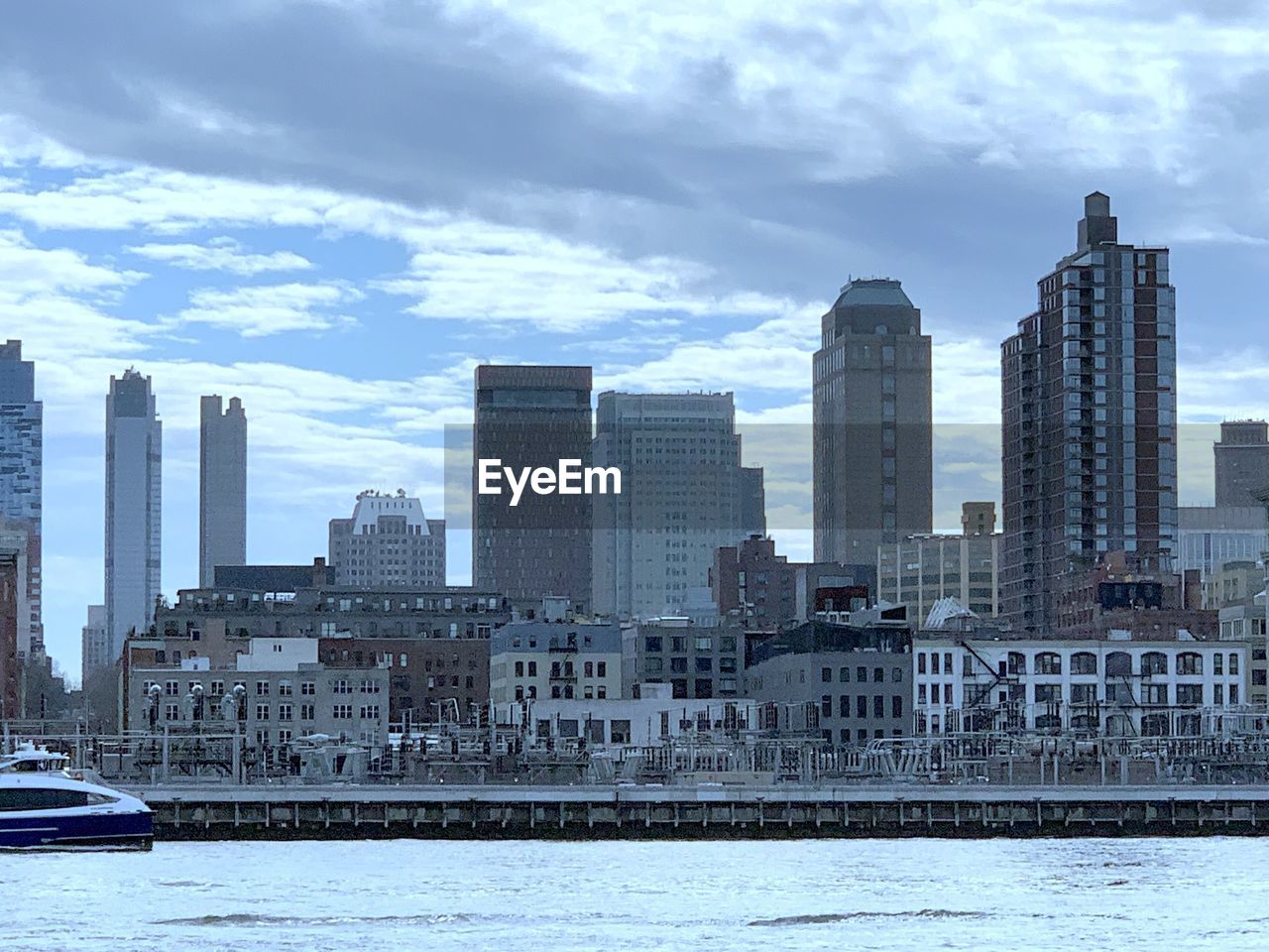 MODERN BUILDINGS BY RIVER AGAINST SKY