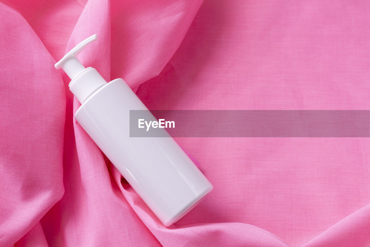 White plasstic bottle isolated on pink color background, fluid pump container for cosmatic product, 